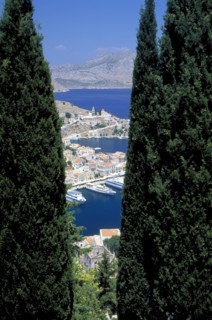 GREECE, Dodecanese, Symi, Gialo.  The town and harbour partly viewed between trees in the