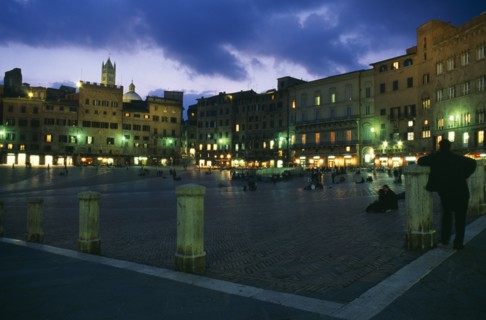 ITALY, Tuscany, Siena, Piazza del Campo.  Night view over Il Campo and cafes with people walking or