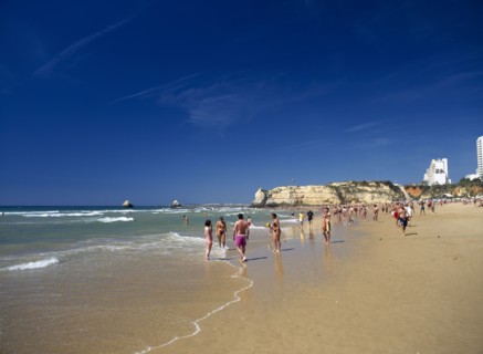 PORTUGAL, Algarve, Praia da Rocha, View along beach with people walking along the waters edge