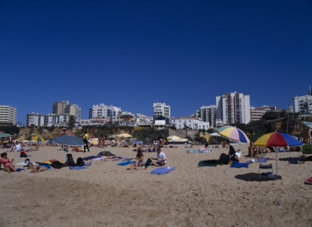 PORTUGAL, Algarve, Praia da Rocha, View of beach with people sunbathing and clifftop hotels behind