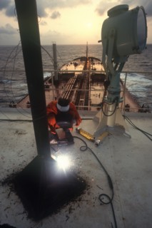 INDUSTRY, Welding, Man using electric arc welder on board a ship in Indonesia.
