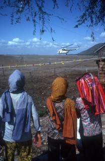 CAMBODIA, Tinh Bien, Three figures in the foreground watching a UN helicopter on the Vietnamese
