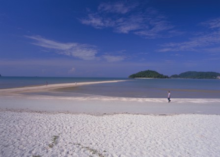 MALAYSIA, Langkawi, Kedah, Pantai Cenang beach with man walking near the the sand bar at low tide