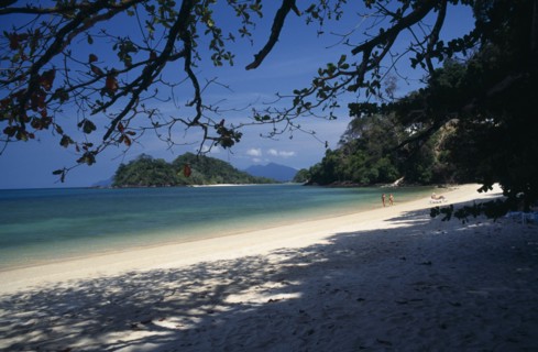 MALAYSIA, Kedah, Langkawi, Datai Bay beach with tourists walking by the water’s edge looking out to