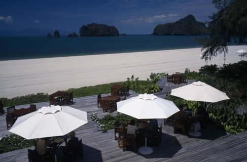 MALAYSIA, Kedah, Langkawi, Tourists sitting under umbrellas set on decking at the garden restaurant