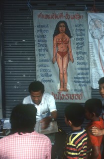 THAILAND, Market, Fortune teller giving a reading watched by children.