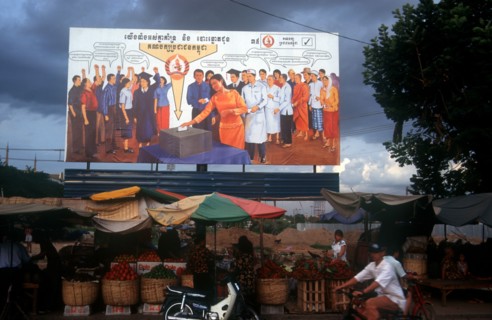 CAMBODIA, Phnom Pehn, Election poster with line of stalls selling fruit along the roadside in front