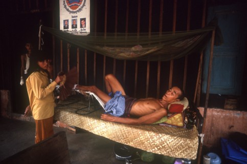 CAMBODIA, Kompong Thom, M.S.F hospital.  Woman fanning male patient lying on a bed.