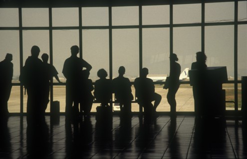 VIETNAM, Hanoi, People at the airport terminal viewed from behind silhouetted against the window.