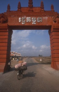 CAMBODIA, Moc Bai, Man on a bicycle crossing the border between Cambodia and Vietnam underneath
