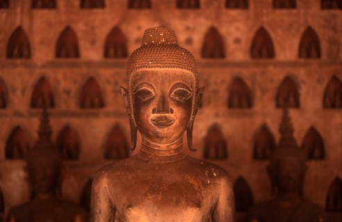 LAOS, Vientianne, Wat Si Saket.  Detail of Buddha figure in the foreground with niches containing