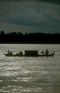 CAMBODIA, Stung Treng, "Narrow barge on the Mekong River, oarsmen silhouetted against sparkling