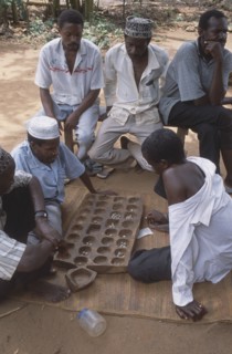 TANZANIA, Zanzibar Island, People, Group of young men playing traditional board game.