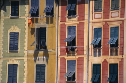 ITALY, Liguria, Portofino, Green yellow and red painted buildings with blue shutters by the harbour