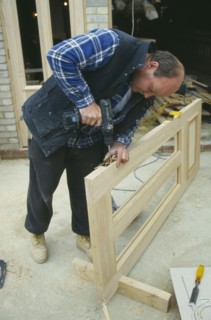 ARCHITECTURE, Construction, Carpentry, Carpenter using power screwdriver to secure hinge to door