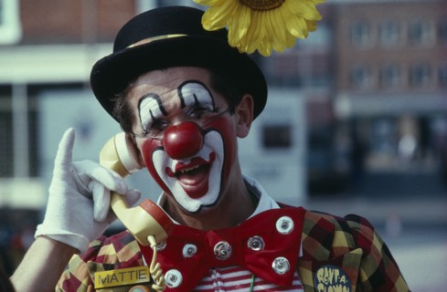 COMMUNICATIONS, Phones, Clown holding the handpiece of a phone to his ear and laughing