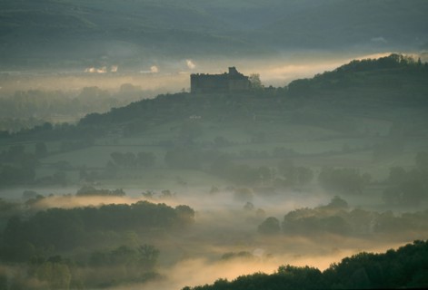 FRANCE, Aquitaine, Dordogne, "Castelnau-Bretenoux Castle silhouetted on hillside against pale,
