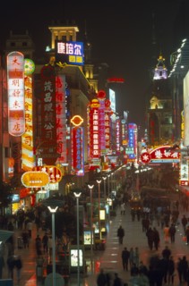 CHINA, Shanghai, Busy pedestrianised street with neon signs and advertising hoardings illuminated