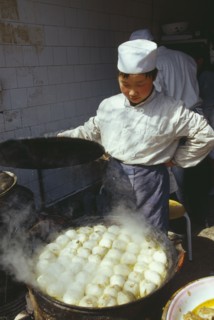 CHINA, Shaanxi Province, Xian, Cook lifting the lid off large dish of frying food.