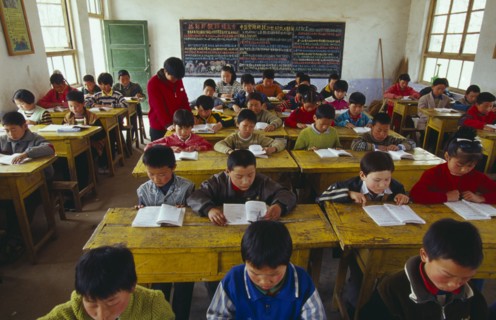 CHINA, Shaanxi Province, Xian, Classroom with school children reading at their desks with a teacher