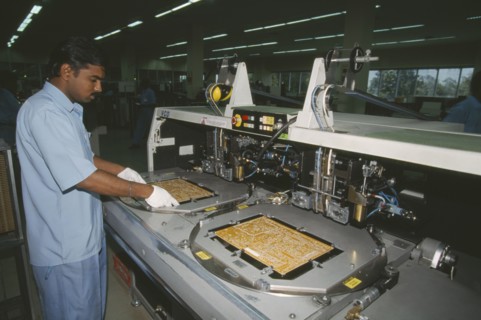 INDIA, Karnataka, Bangalore, Man working in a factory producing circuit boards.