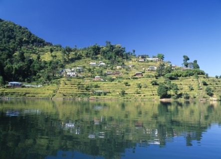 NEPAL, Annapurna Region, Pokhara, View over Lake Phewa with reflected terrace hillside and trees.
