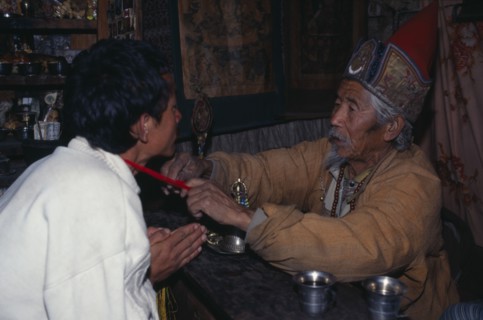 NEPAL, Annapurna Region, Manang, Lama blessing good luck thread for safe journey.  Also known as