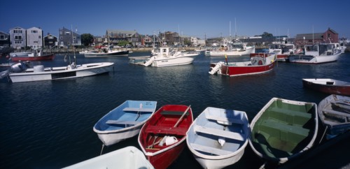 USA, Maine, Rockport, View over painted wooden rowing boats towards waterside buildings.