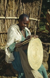 ETHIOPIA, Harerge Province, General, "Woman making circular mat from straw, stitched into place."