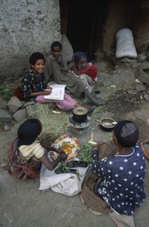 ETHIOPIA, Wolo Province, Lalibela, Group of woman and children sitting around cooking pot on stove