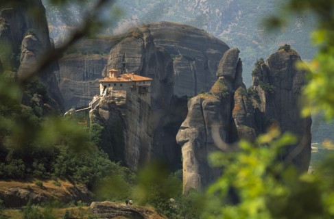 GREECE, Thessalia, Meteora, "Monastery  amongst eroded rock pinnacles, seen through tree branches.