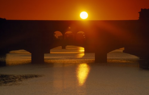 ITALY, Veneto, Florence, Bridge silhouetted against deep red and orange sunset sky seen from