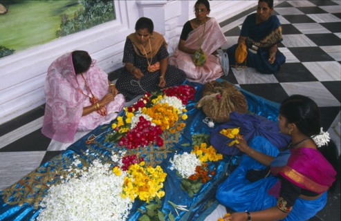 INDIA, Utter Pradesh, Vrindaven, "Women wearing colourful saris making flower garlands, sitting on