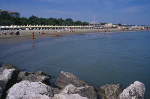 ITALY, Veneto, Venice, "Lido Beach with sun bathers, distant view with rocks in the foreground.   "