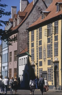 LATVIA, Riga, People walking past tall colourful buildings in the Old Town