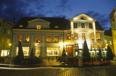 ESTONIA, Tallinn, Raekoja Plats.  Exterior of cafe and restaurant and clothes shop illuminated at