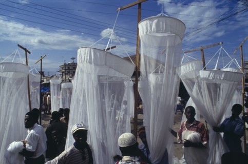 TANZANIA, Dar es Salaam, Mosquito nets for sale at market with men in the foreground and seen
