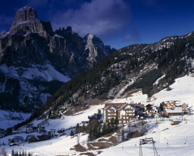 ITALY, Trentino-Alto Adige, Dolomites, Corvara.  Hotels and other buildings in snow covered valley