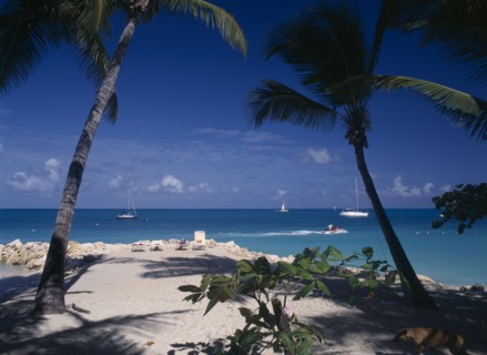 WEST INDIES, Antigua, Dickenson Bay, "Sandy beach and rocks with sunbather on lounger.  Aquamarine