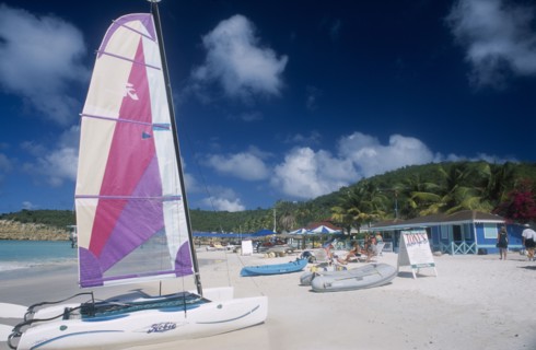 WEST INDIES, Antigua, Dickenson Bay, "Sandy beach with people on deck chairs beside blue painted