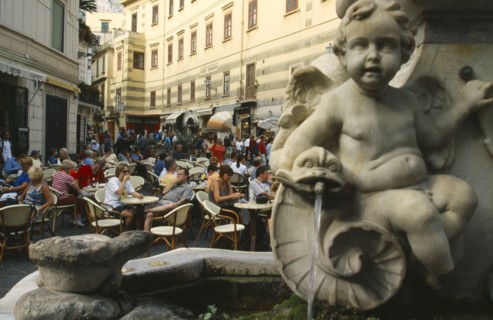 ITALY, Campania, Amalfi Coast, Amalfi.  Street scene with people seated at outdoor tables of busy