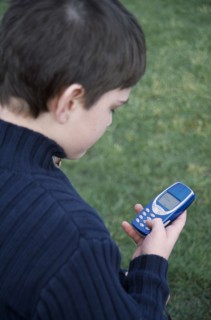 COMMUNICATIONS, Telephones, Mobile, View over the shoulder of a boy holding a blue mobile phone