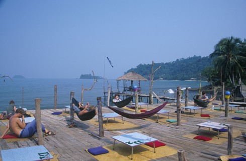 THAILAND, Trat Province, Koh Chang, People lying in hammocks on a wooden platform built over rocks