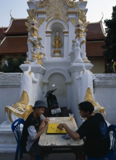 THAILAND, North, Chiang Mai, Wat Mahawan temple with two boys playing go on the pavement below