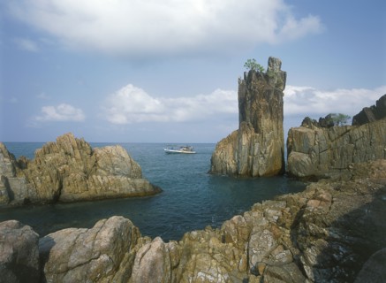 THAILAND, Trat Province, Koh Chang, Laem Chai Chet. Coastal rock formations and cliffs with a small