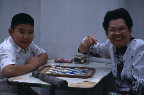 THAILAND, North, Chiang Mai , "Woman and young boy playing drafts, turned to camera smiling and