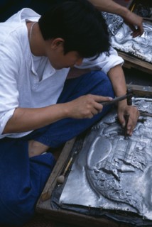 THAILAND, North, Chiang Mai , Tha Phae Road.  Young man working on metal work relief picture.