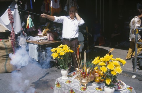THAILAND, North, Chiang Mai, "Chinese New Year.  Man at roadside stall holding his ears as he sets