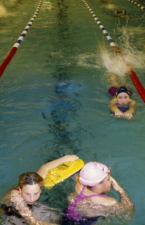 20022539 SPORT Swimming Swimming Pool Three girls at swimming club practice in pool with floats.