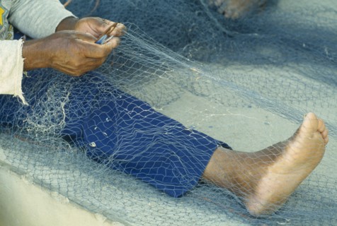 WEST INDIES, St Lucia, Anse La Raye, "Fishermen repairing nets on the beach, view of bare feet,